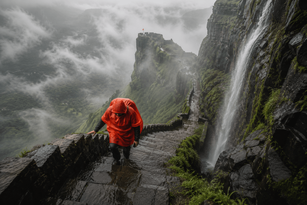 A trekker ascending rain-slicked stone steps on a Sahyadri fort - Maharashtra Fort Trek Guide 2026
